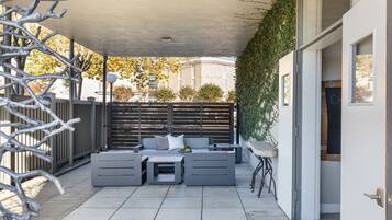 An outdoor patio with a grey sofa set, a small table, and a chair.