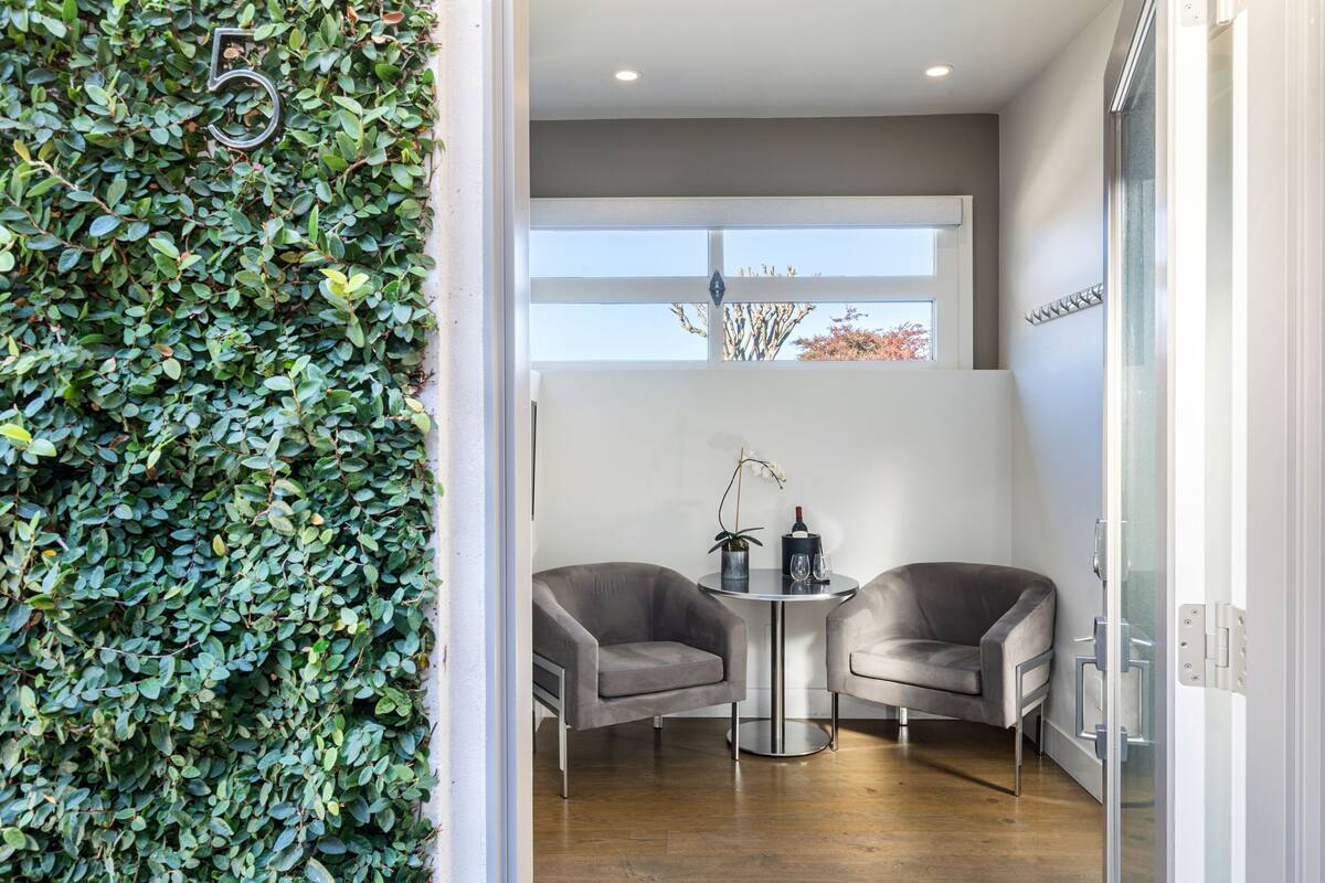 A modern room with two grey armchairs, a small round table, and a glass partition.