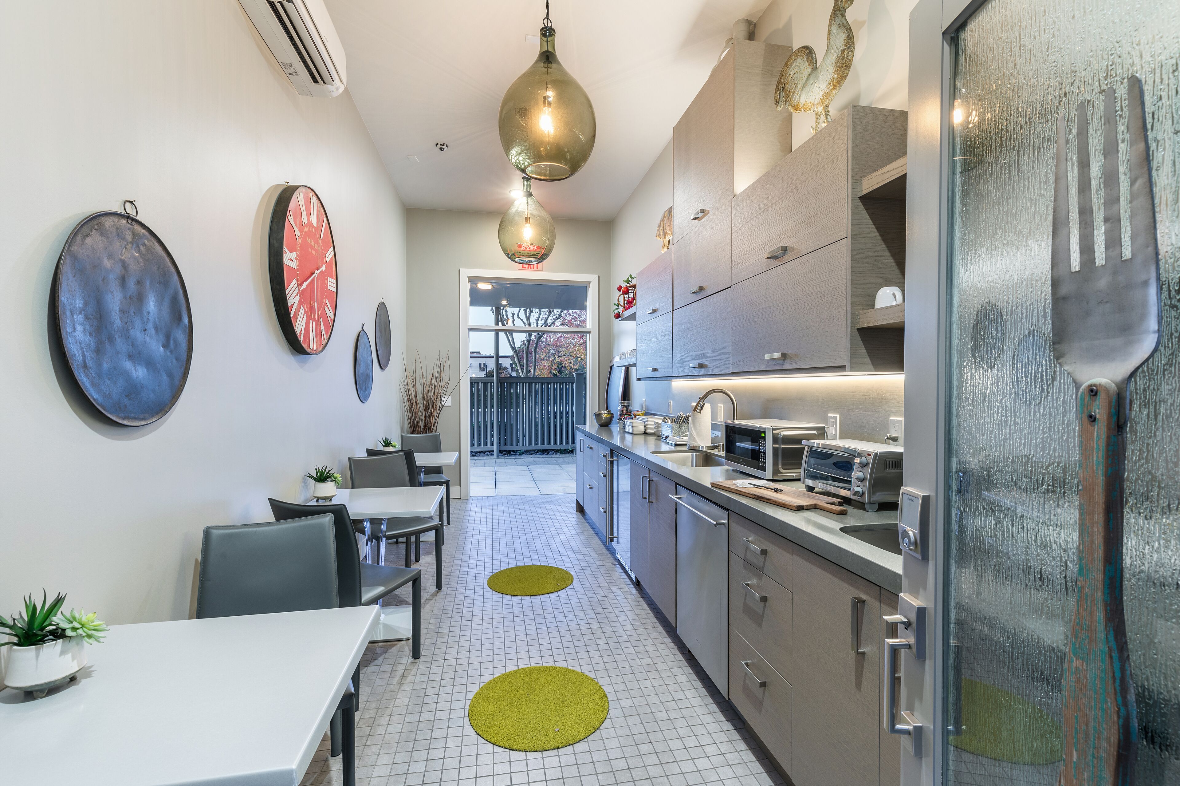 A modern kitchen with a dining area, featuring a long countertop, cabinets, and a unique glass door with a metal handle.