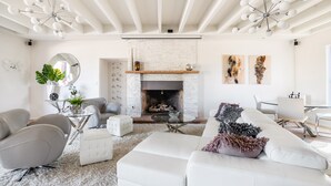 Una sala de estar moderna con chimenea, sofás blancos y un comedor.