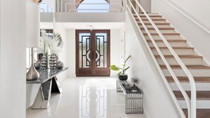 Un interior moderno con una escalera, piso pulido y una puerta decorativa.