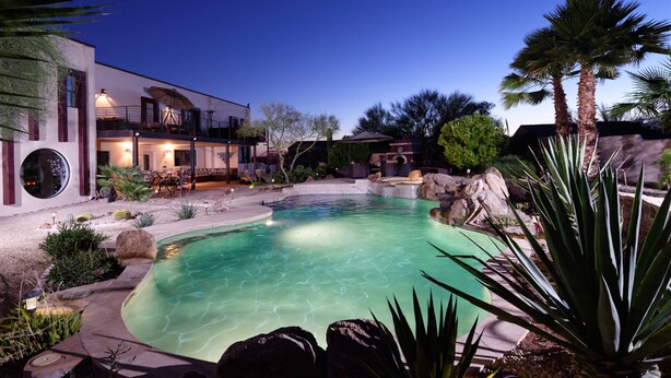 Una casa moderna con piscina, muebles de jardín y un jardín bien cuidado.