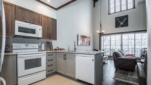 A modern kitchen with wooden cabinets, a built-in microwave, and a dishwasher. - Cozy condo - Walk to village/mountain - Monthly rates (Mont-Tremblant)