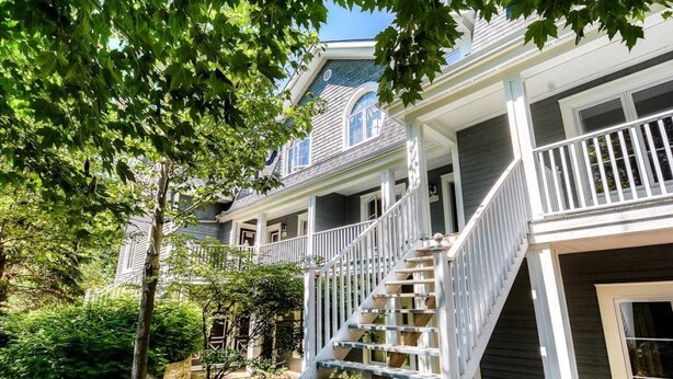 A two-story house with a front porch, a staircase, and a garden area. - Cozy condo - Walk to village/mountain - Monthly rates (Mont-Tremblant)
