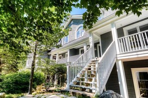 A two-story house with a front porch, a staircase, and a garden area. - Cozy condo - Walk to village/mountain - Monthly rates (Mont-Tremblant)