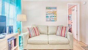 A living room with a beige sofa, striped pillows, a television, and a bookshelf. -  24 hour gated community Beach House , Surfside Beach  SC (Surfside Beach)