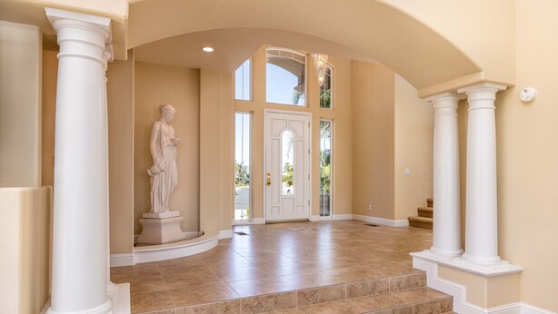 A grand entrance with a statue, a double door, and a staircase leading to the upper level.