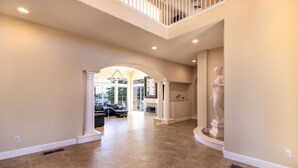 A spacious living area with a high ceiling, a fireplace, and a statue.