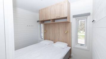 A bedroom with a bed, wooden headboard, built-in shelves, a window, and a door.