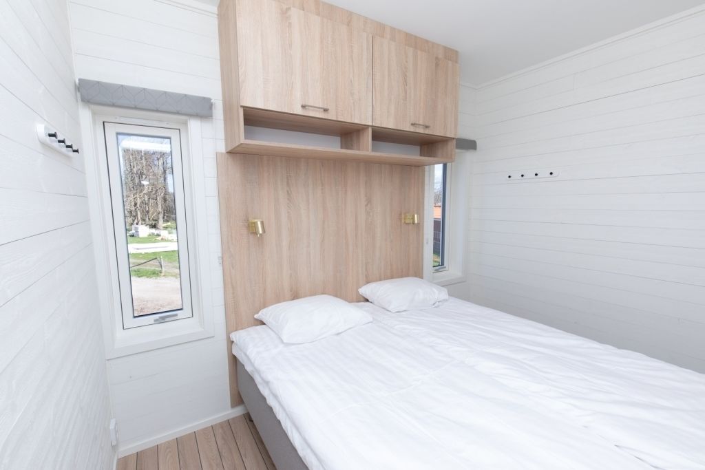 Un dormitorio con cama, ventana y cabecera de madera.