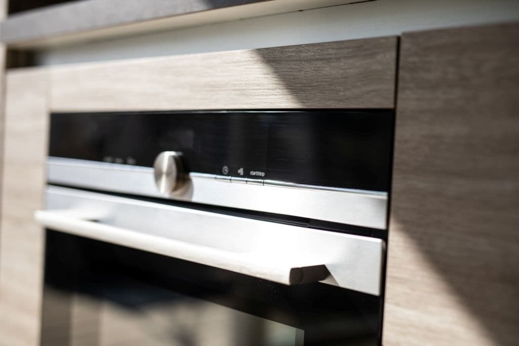 A modern kitchen with stainless steel appliances, a wooden countertop, and a built-in oven.
