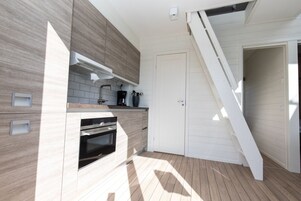 Una cocina moderna con horno empotrado y una escalera que sube a un nivel superior.