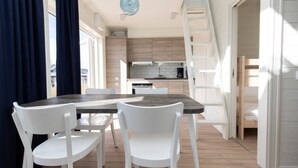 Una cocina moderna con armarios de madera, una mesa de comedor con sillas blancas y una lámpara colgante azul.