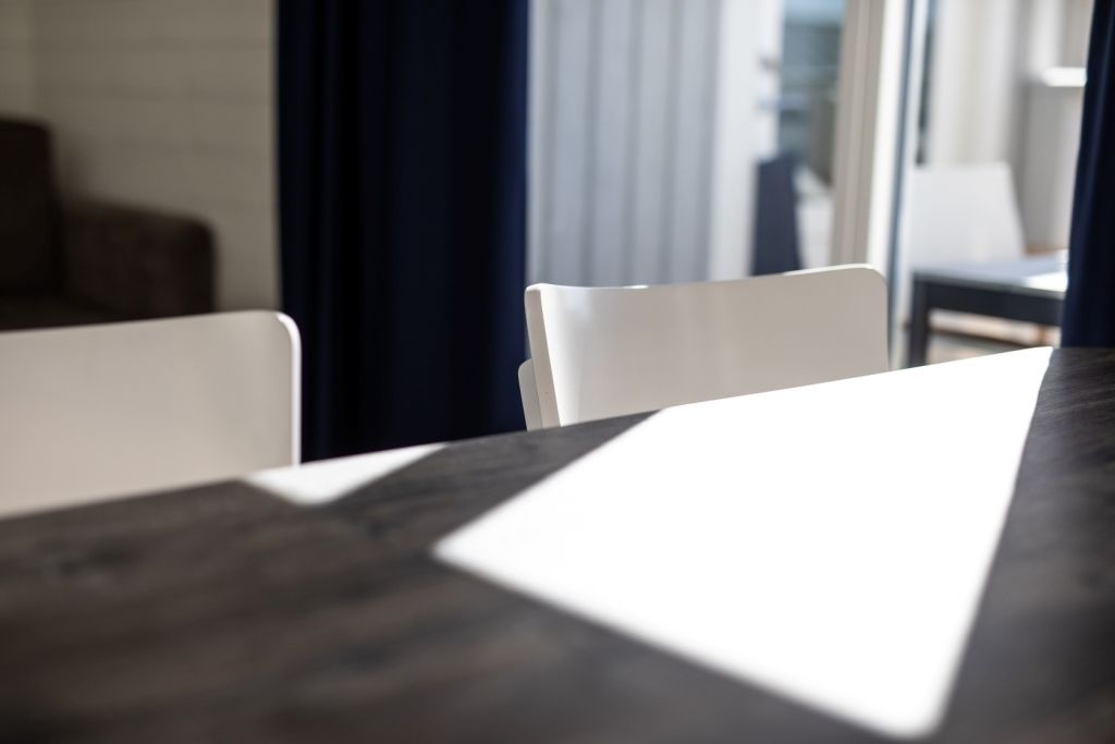 A dining area with a dark wooden table and white chairs.