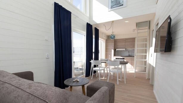 Un espacio habitable compacto con sofá, mesa de comedor, sillas y zona de cocina.