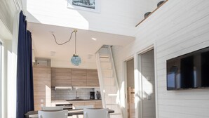 Una cocina moderna con armarios blancos, un comedor con sillas blancas y una mesa redonda con un centro decorativo.
