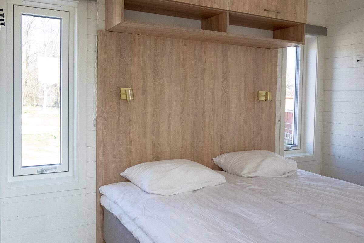 A bedroom with a bed, wooden headboard, and built-in shelving.