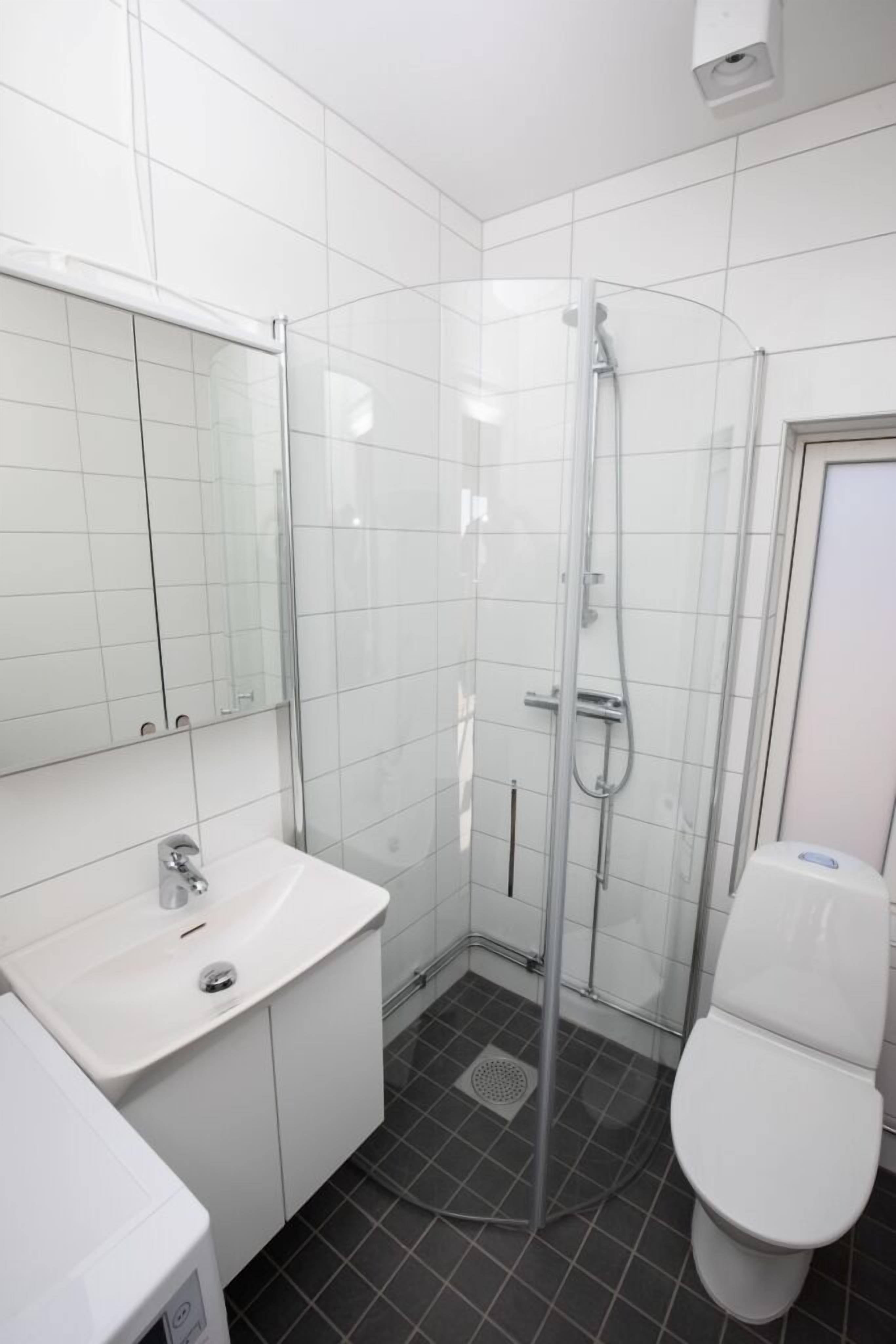 A modern bathroom with a glass-enclosed shower, a white sink, and a toilet.