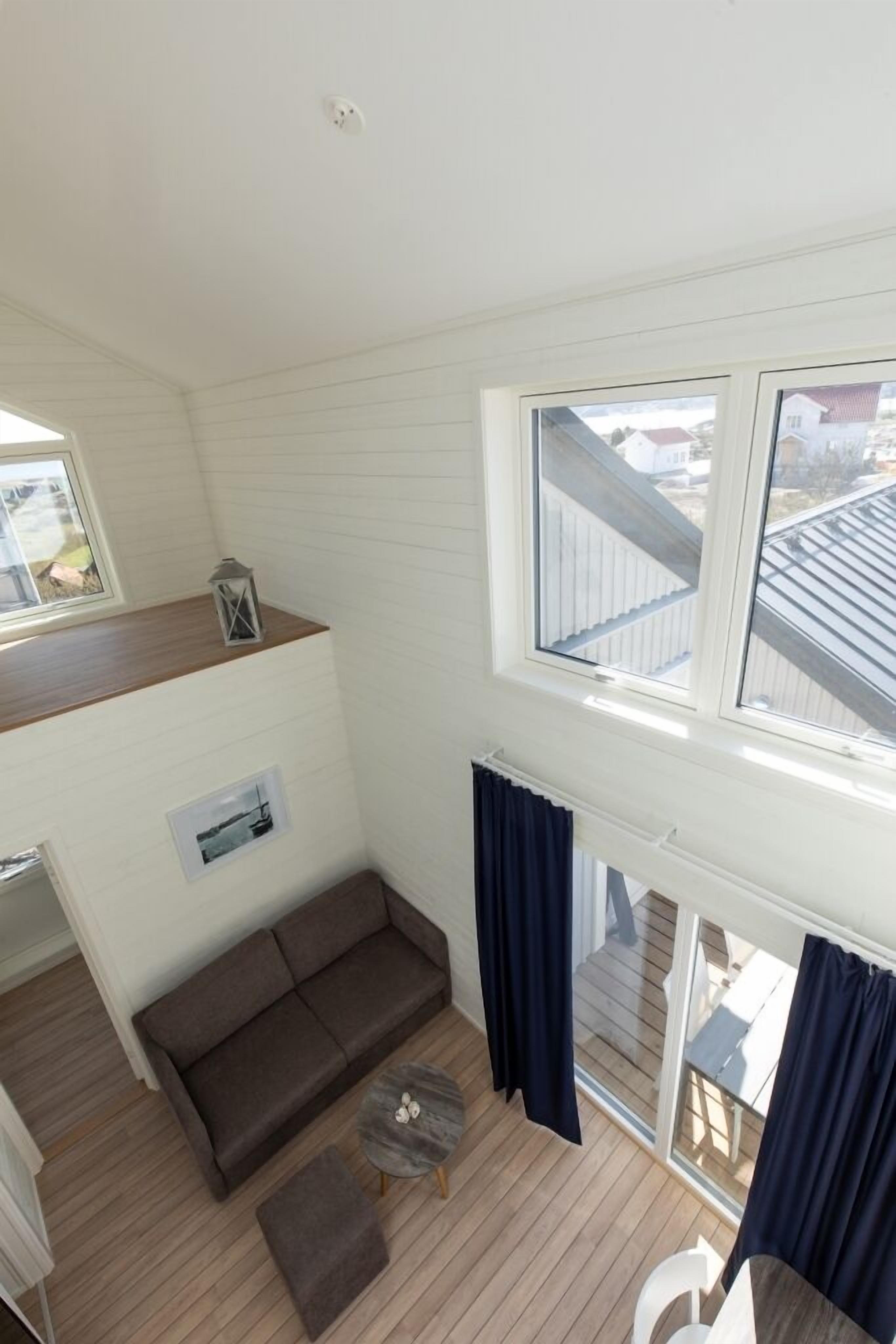 A compact living space with a sofa, a small table, and a window overlooking a residential area.