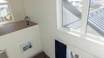 A compact living space with a sofa, a small table, and a window overlooking a residential area.