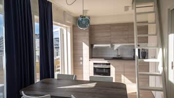 A modern kitchen with wooden cabinets, a built-in oven, and a dining area with a wooden table and white chairs.