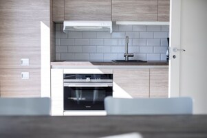 Una cocina moderna con horno empotrado, grifo de acero inoxidable y armarios de madera clara.