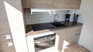 Una cocina moderna con horno empotrado, un lavamanos y una cafetera.