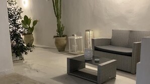 A modern outdoor seating area with wicker furniture, potted plants, and a glass coffee table. - Clara Domus (Gallipoli)