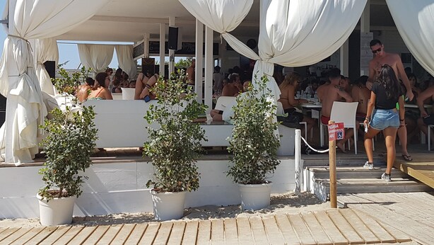 An outdoor seating area with white canopies, potted plants, and a wooden deck. - Clara Domus (Gallipoli)