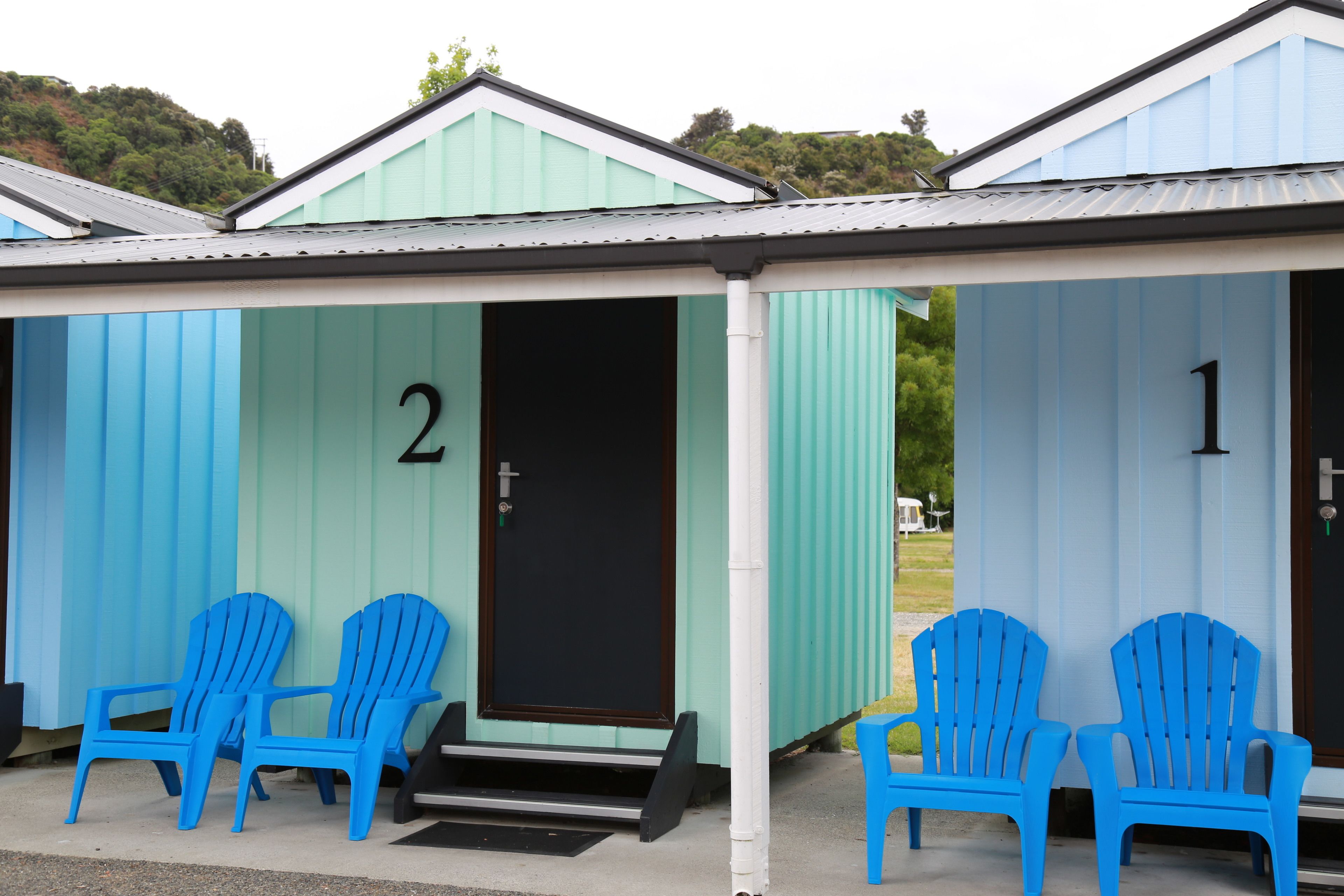 A row of two-room cabins numbered 1 and 2, each with a door and a small porch area.