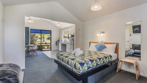 A modern hotel room with a large bed, a desk, and a bathroom. - Kaiteriteri Reserve Cabins (Kaiteriteri)