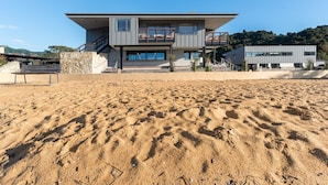 A modern two-story house with a flat roof, large windows, and a balcony. - Kaiteriteri Reserve Cabins (Kaiteriteri)
