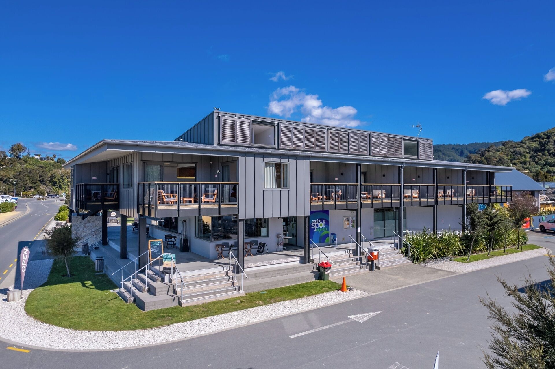 A modern hotel with a two-story structure, outdoor seating area, and a view of the surrounding landscape.