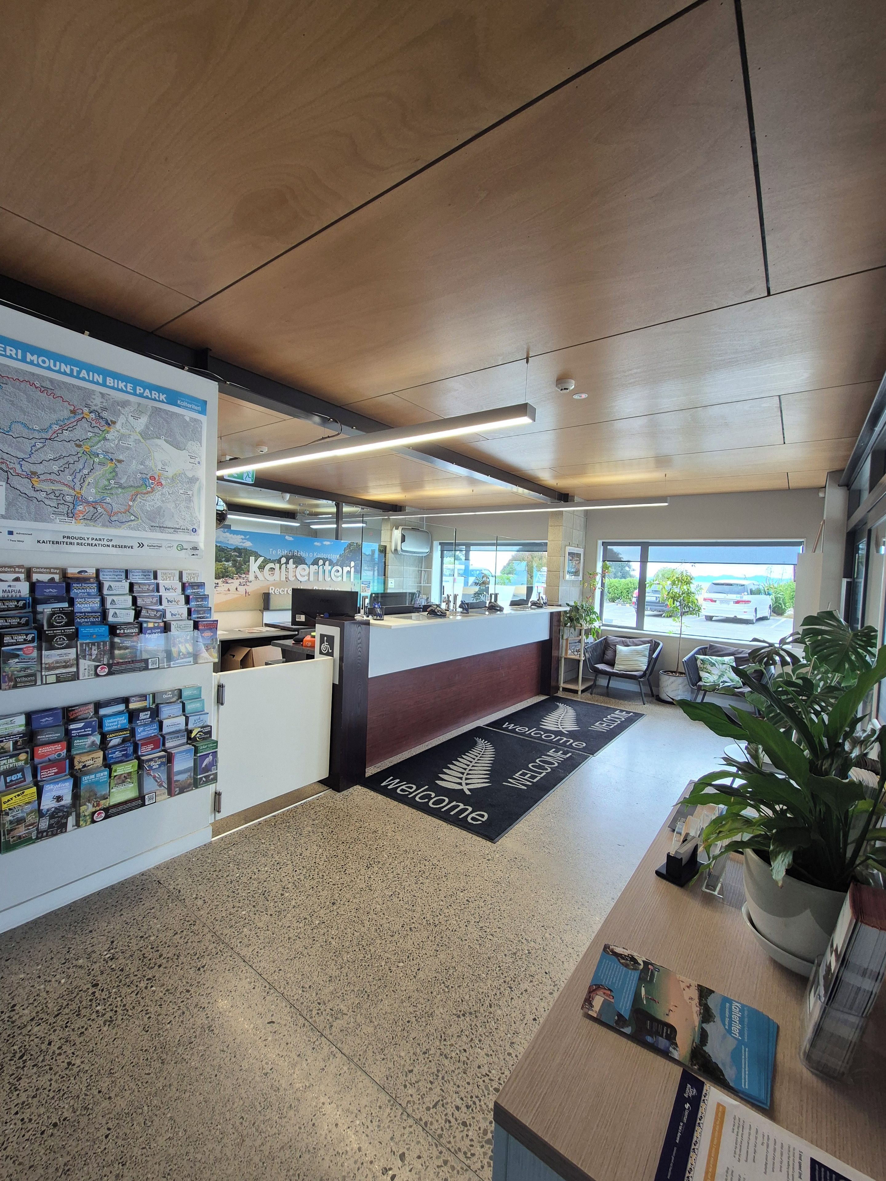A reception area with a map, informational brochures, a reception desk, seating area, and a view of the outside.