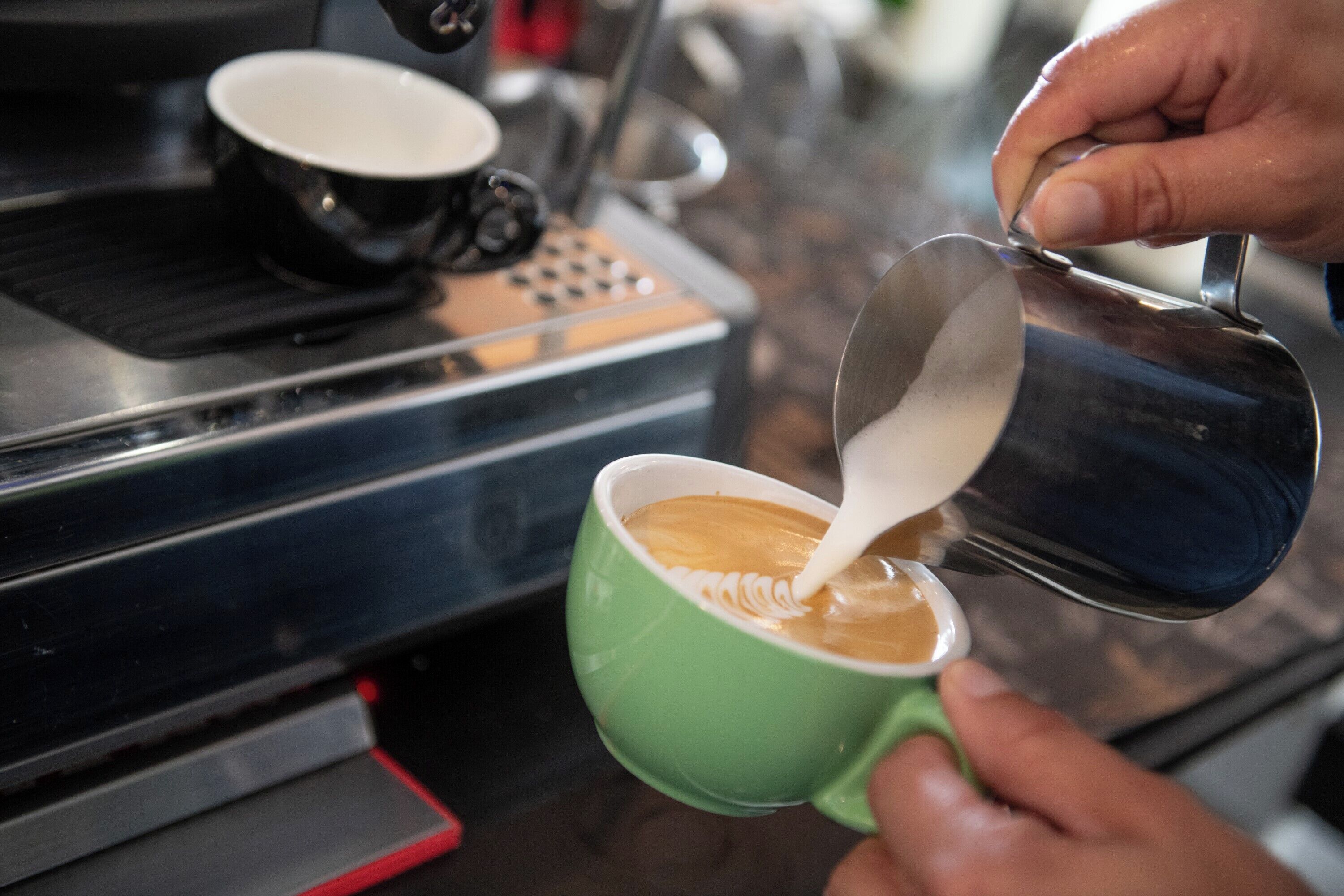 A person pouring milk into a cup of coffee.