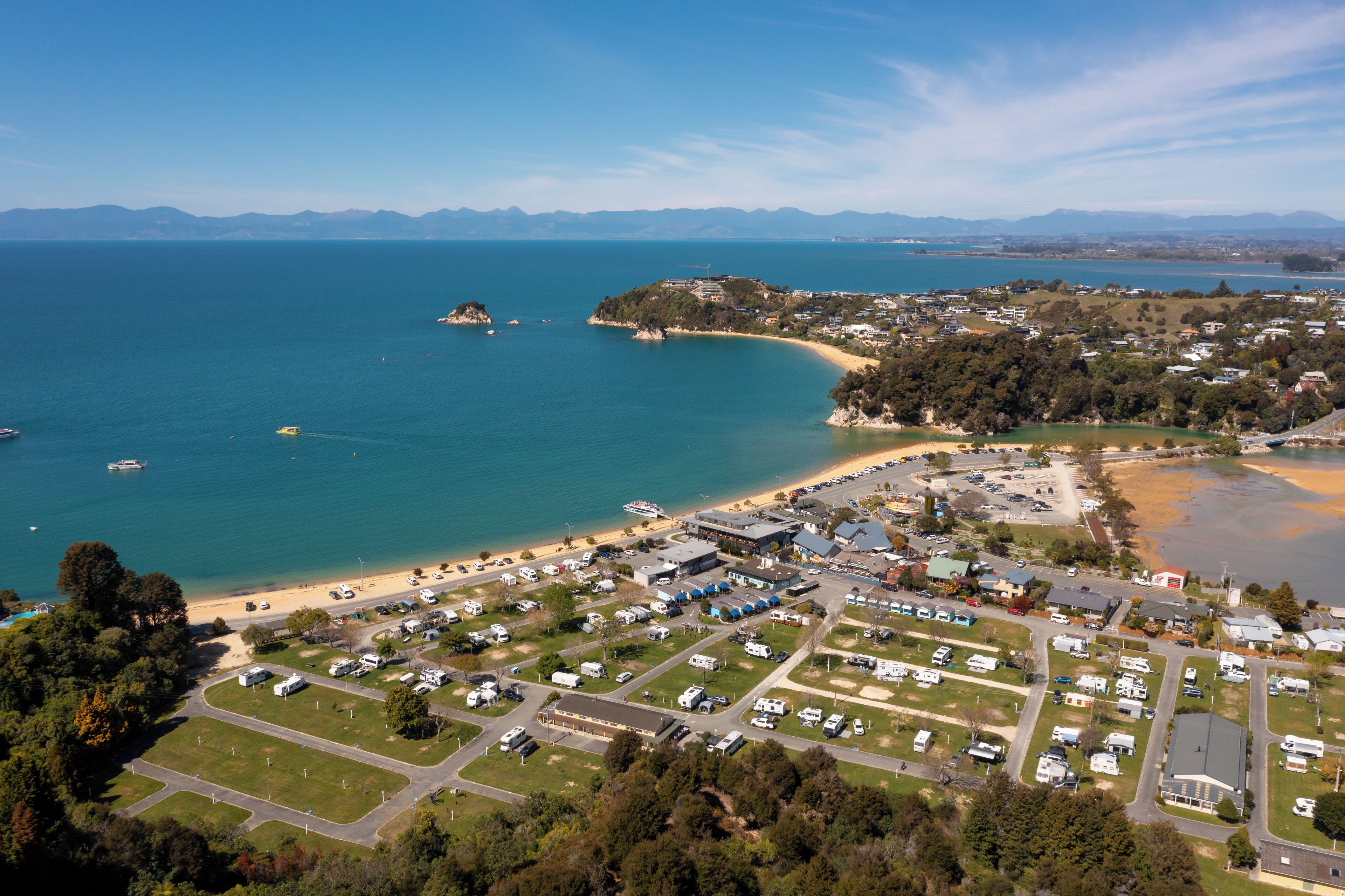 An aerial view of a coastal area with a marina, beach, and residential buildings.