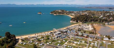 An aerial view of a coastal area with a marina, beach, and residential buildings.