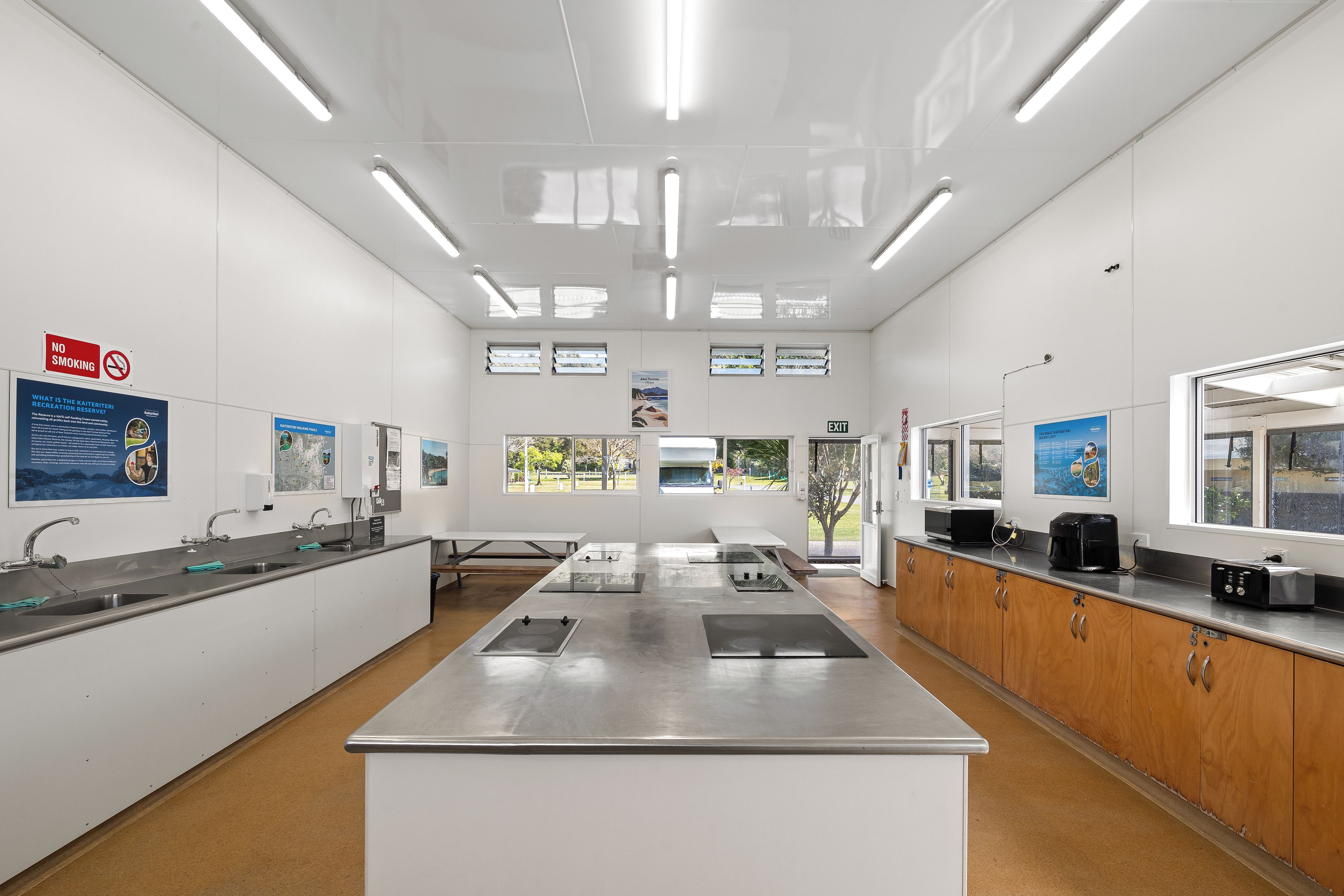 A clean, modern kitchen with stainless steel appliances, a central island, and a view of the outdoors through large windows.
