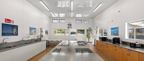 A clean, modern kitchen with stainless steel appliances, a central island, and a view of the outdoors through large windows.