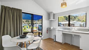 A modern kitchen with a dining area, large windows, and a view of the outdoors.