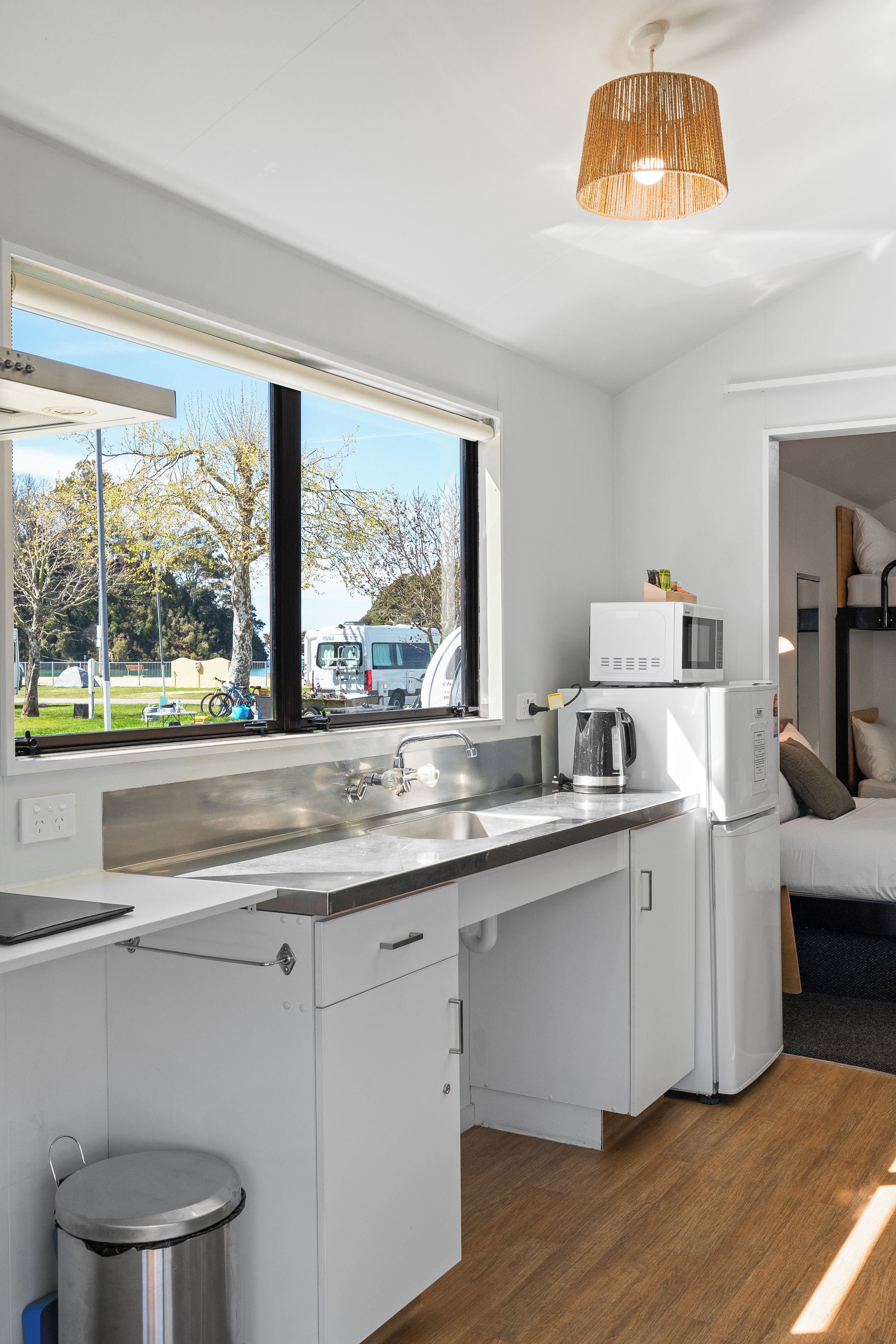 Una cocina compacta con ventana, hervidor, microondas y lavabo.