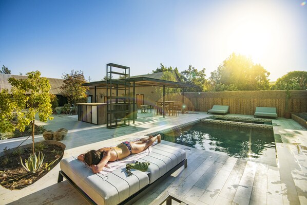 Een buitenzwembad, parasols bij het zwembad en ligstoelen