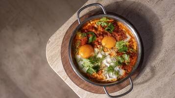 Un plato de shakshuka con huevos sobre una tabla de madera.