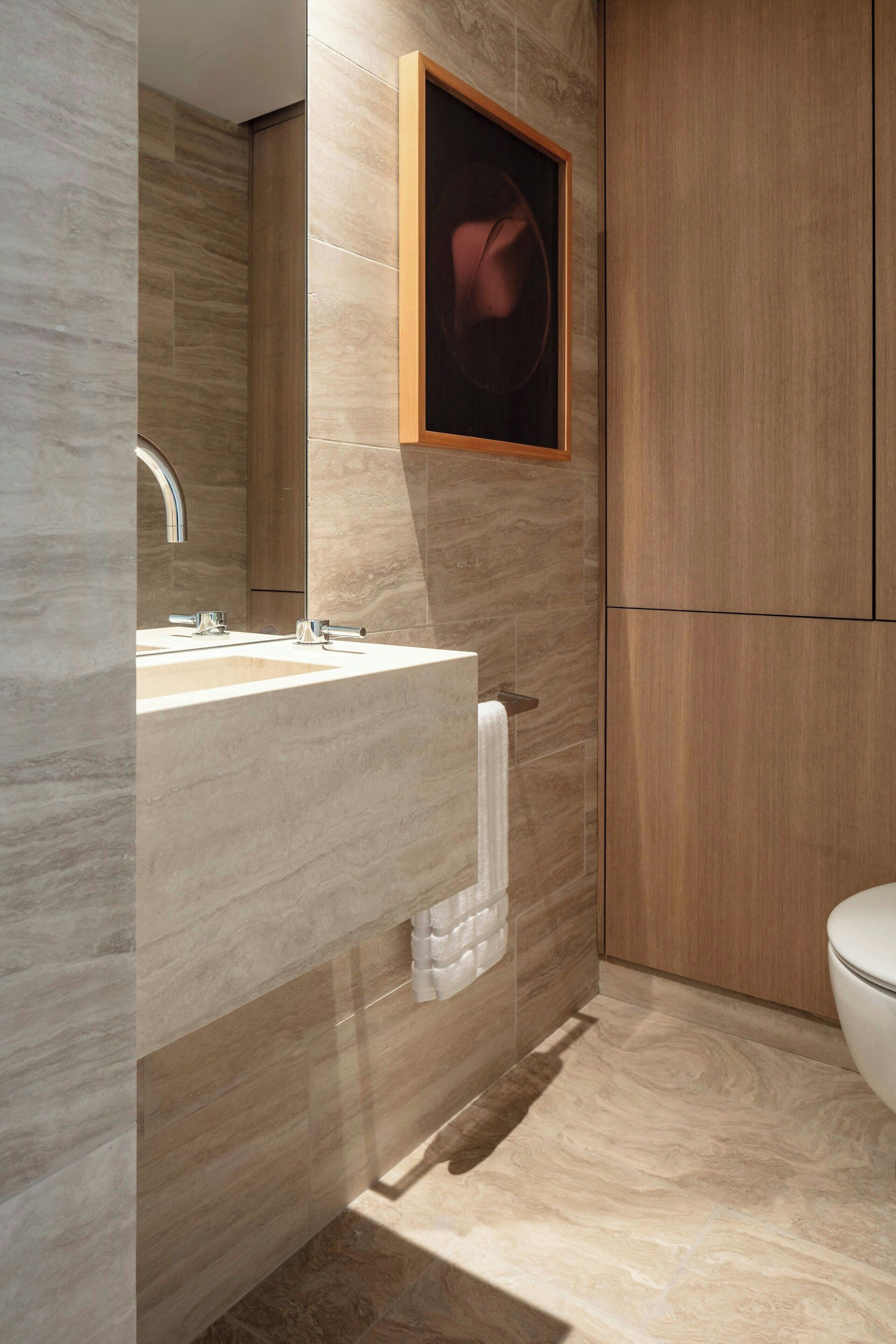 A modern bathroom with a marble sink, a large mirror, and a wooden cabinet.