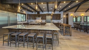 Une cuisine spacieuse dotée d’un grand îlot central, de tabourets de bar et d’un coin bar en bois.