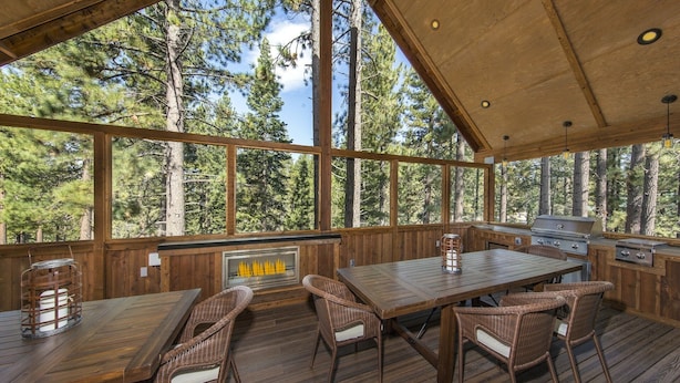Une terrasse en bois avec une table et des chaises, un barbecue et une cheminée.