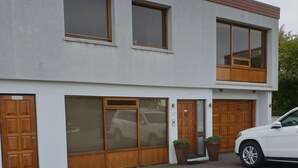 A two-story building with a garage door, a large window, and a potted plant. - Apartm. in a family house with 2 bedr. and a living room with 2 beds (RVK)