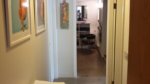 A hotel hallway with framed artwork on the walls, a bed with neatly folded towels, and a door leading to another room. - Apartm. in a family house with 2 bedr. and a living room with 2 beds (RVK)