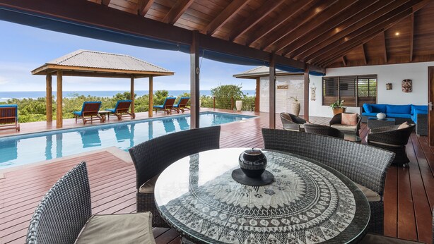 A covered outdoor area with a pool, lounge chairs, and a dining table. - Sea Winds Luxury Villas (Korolevu)