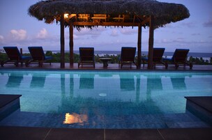 Una piscina al aire libre, sillones reclinables de piscina